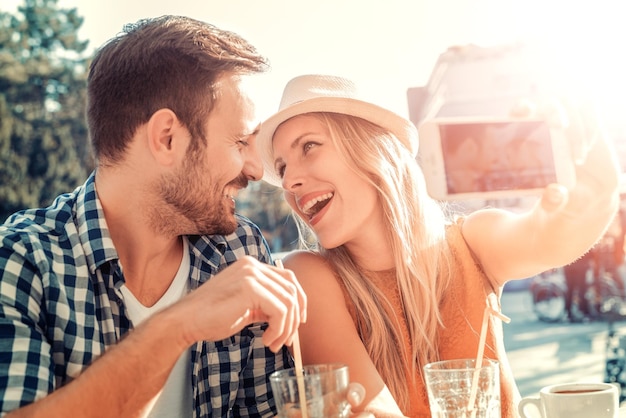 Casal apaixonado tirando uma selfie em um café