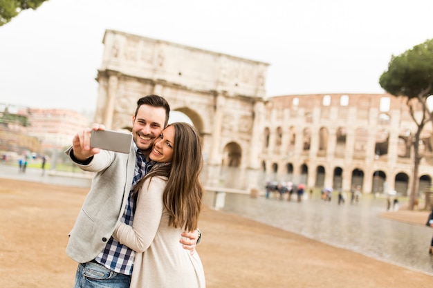 Casal apaixonado tomando selfie na frente do coliseu