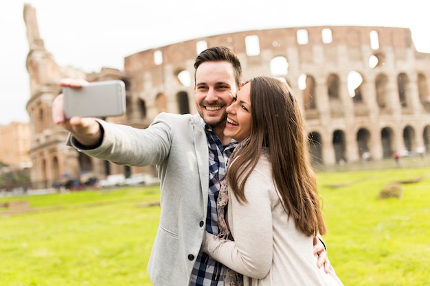 Casal apaixonado tomando selfie na frente do Coliseu