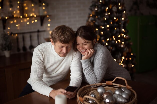 Casal apaixonado usando telefones para enviar mensagens de texto ou fazer compras online em casa