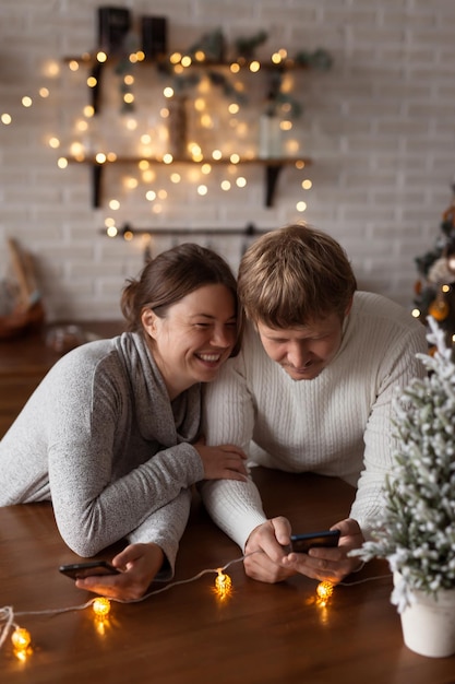 Casal apaixonado usando telefones para enviar mensagens de texto ou fazer compras online em casa