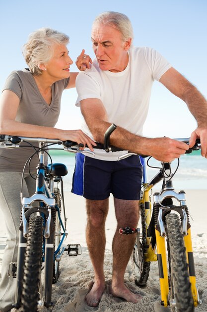 Casal aposentado com suas bicicletas na praia