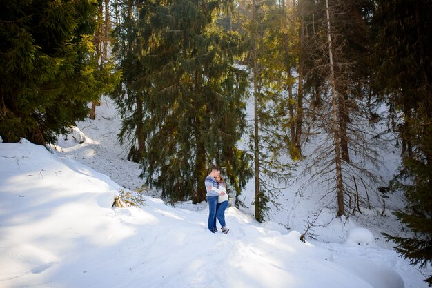 Casal arrebatador, abraçando-se na floresta de inverno.