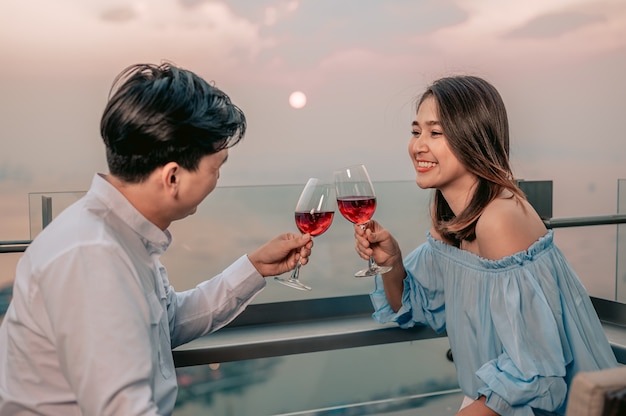 Casal asiático comemora vinho com vista romântica na mesa do restaurante hotelvacationdinner