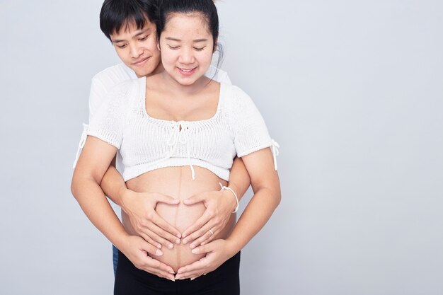 Casal asiático interessante, mãe grávida feliz e pai isolado na superfície branca, Dia Internacional da Família