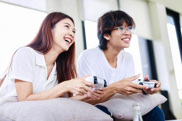 Casal asiático jogando videogame juntos em casa Atividades de lazer de pessoas