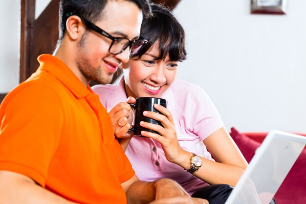 Casal asiático no sofá com um laptop