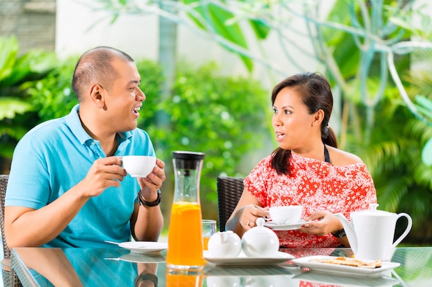 Casal asiático tomando café na varanda de casa