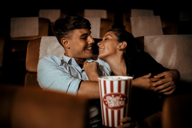 Casal assiste filme no cinema com sorriso de pipoca e sorriso no rosto