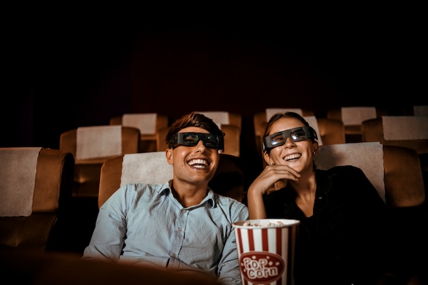 Casal assiste filme no cinema com sorriso de pipoca e sorriso no rosto