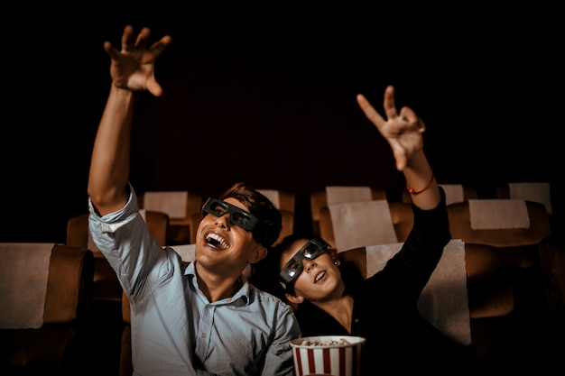 Foto casal assiste filme no cinema com sorriso de pipoca e sorriso no rosto