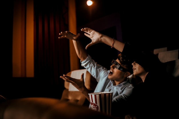 Casal assiste filme no cinema com sorriso de pipoca e sorriso no rosto