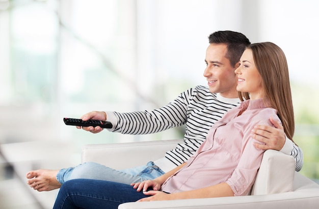 Casal assistindo tv em sua sala de estar em casa, jovem sorriso feliz homem e mulher sentada no sofá,