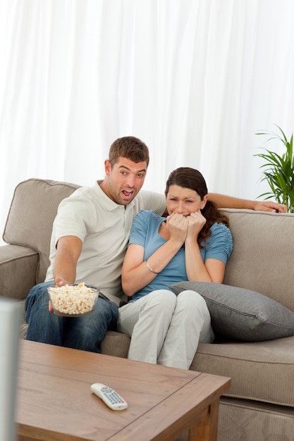 Casal aterrorizado assistindo um filme de terror na sala de estar