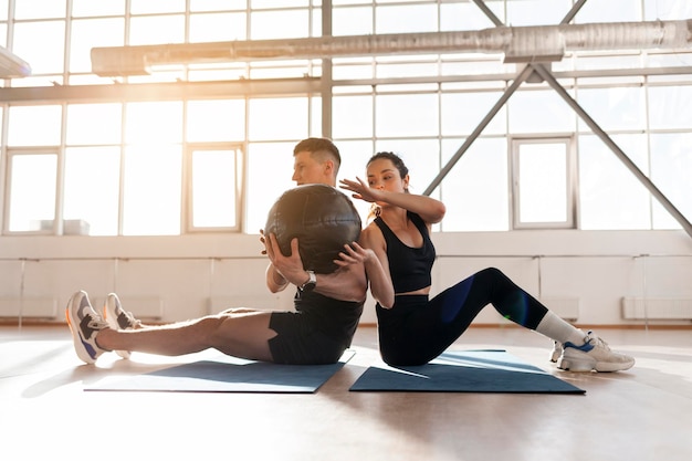 Casal atlético em roupas esportivas em treinamento de crossfit com bola na sala mulher e homem juntos