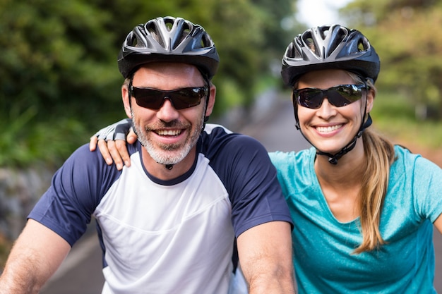 Casal Atlético usando capacete enquanto andava de bicicleta