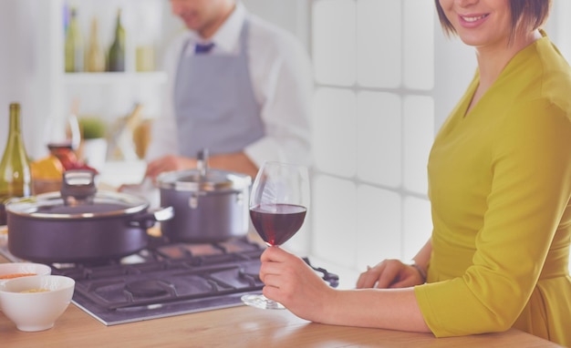 Casal atraente apaixonado por cozinhar e abre o vinho na cozinha enquanto cozinha o jantar para uma noite romântica