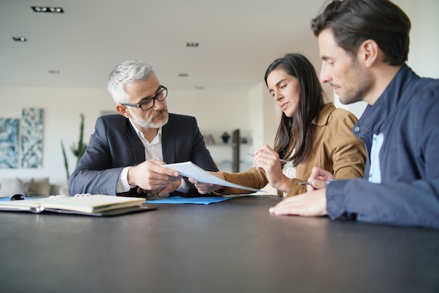 Casal atraente, assinando contrato com o agente imobiliário na casa contemporânea