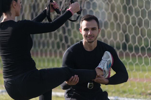 Foto casal atraente fazendo crossfit com tiras de fitness trx na área do parque da cidade treinamento e exercício para o conceito de estilo de vida saudável de resistência ao ar livre