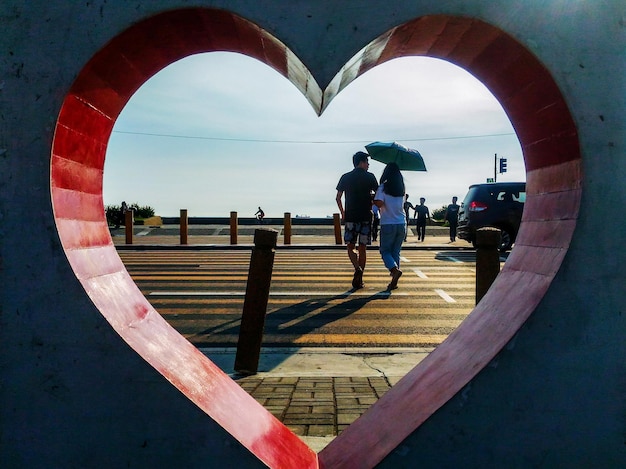 Foto casal atravessando o pedestre enquanto enquadrado por um coração