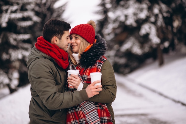 Casal bebendo café e caminhando no parque de inverno