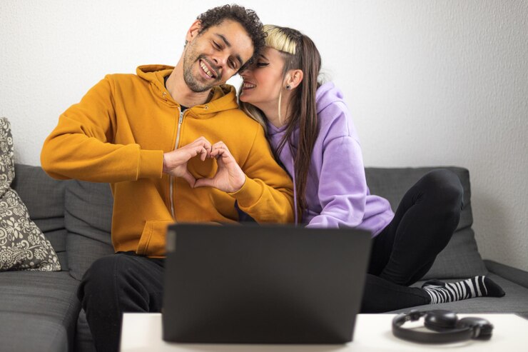 Foto casal biracial conversando por videochamada com sua família brasileira ele faz um símbolo de coração com as mãos