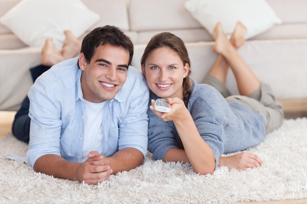 Casal bonito assistindo TV enquanto estava deitado em um tapete