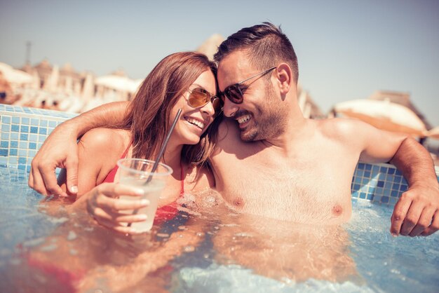 Casal bonito bebendo cocktails na piscina