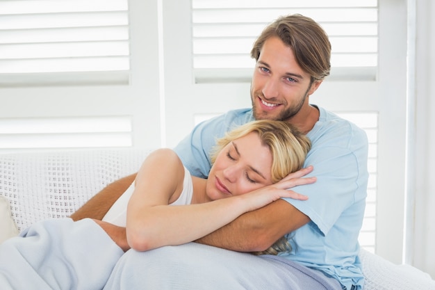 Casal bonito e casual sentado no sofá sob o cobertor