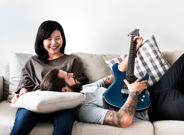 Casal bonito em um namorado de sofá tocando um violão e conceito de amor