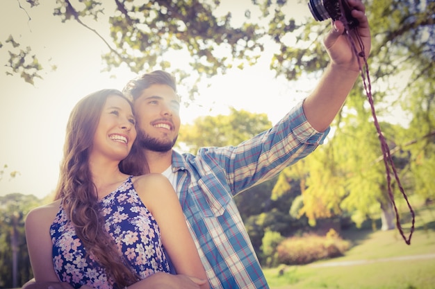 Foto casal bonito fazendo selfie com câmera retro no parque