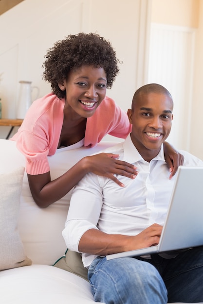 Casal bonito relaxando no sofá com laptop