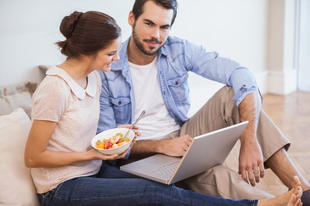 Casal bonito sentado no chão usando o laptop