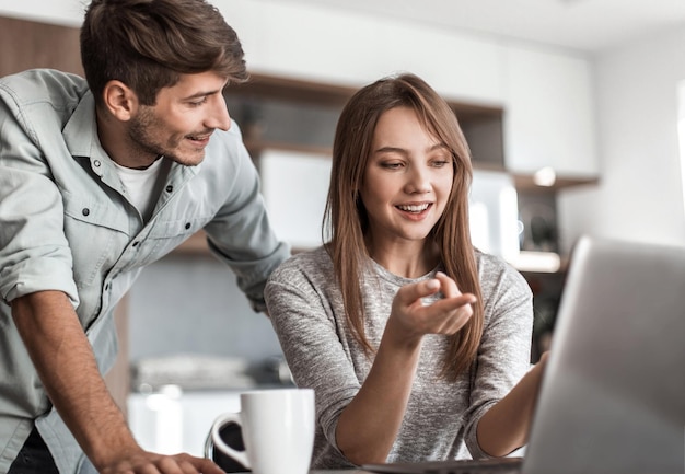 Casal bonito usando laptop juntos em casa na cozinha