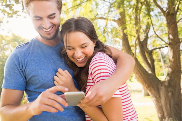 Casal bonito usando o telefone móvel no parque