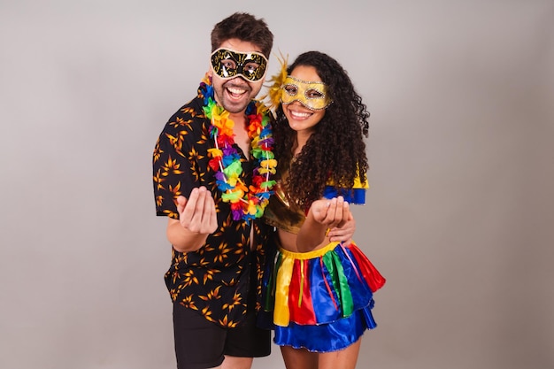 Casal brasileiro com roupas de carnaval convidando as mãos venham bem-vindos