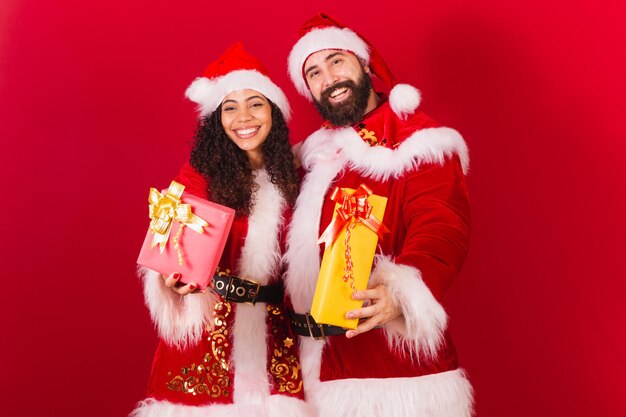 Casal brasileiro vestido para o natal papai noel múmia noel trocando presentes aprovados mulher negra e homem caucasiano