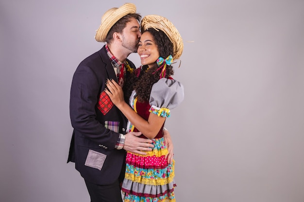 Foto casal brasileiro vestindo roupas de festa junina confraternização em nome de são joão arraial trocando beijo