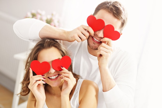 Casal brincalhão com corações no quarto