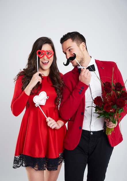 Foto casal brincalhão com máscaras e buquê de rosas
