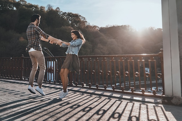 Casal brincalhão. Comprimento total do lindo jovem casal de mãos dadas e girando