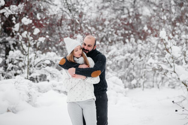 Casal brincando com a neve na floresta.