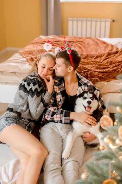 Casal brincando com cachorro no quarto