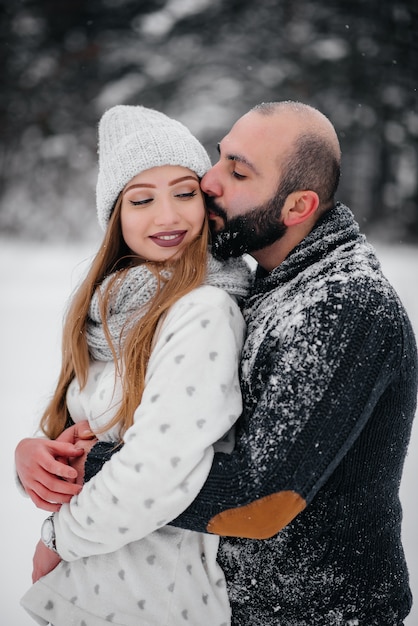 Casal brincando com neve na floresta