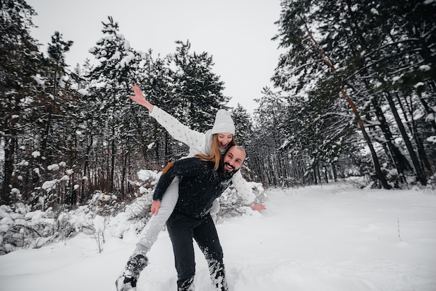 Casal brincando com neve na floresta.