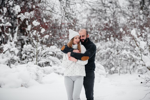 Casal brincando com neve na floresta