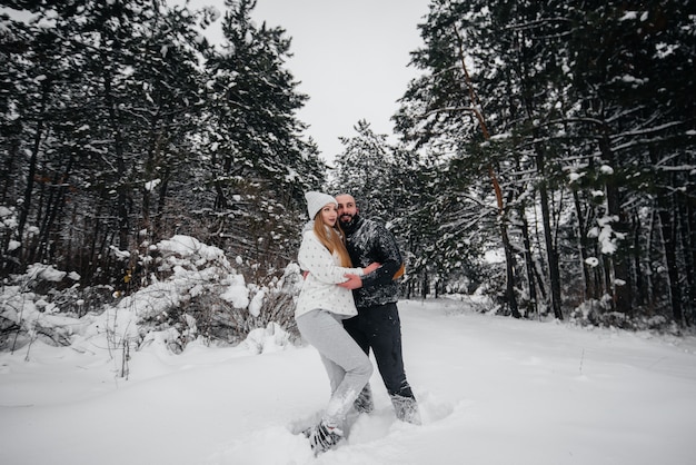 Casal brincando com neve na floresta