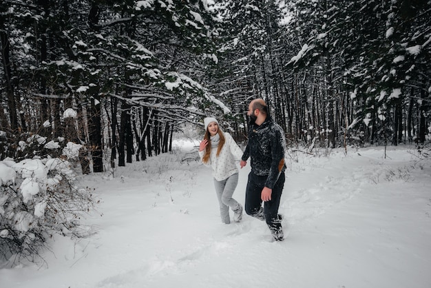 Casal brincando com neve na floresta