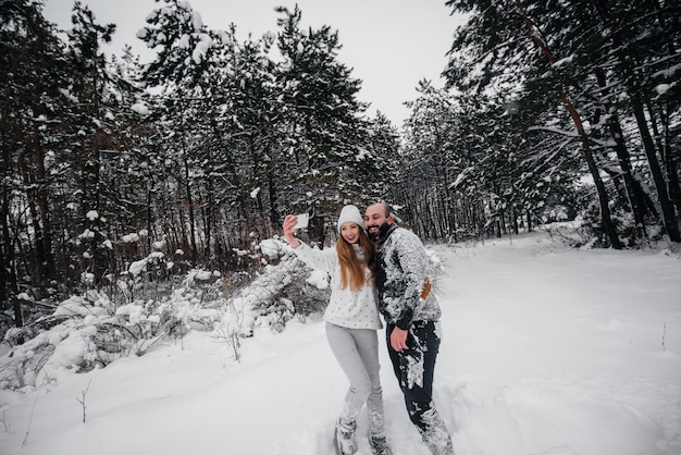 Casal brincando com neve na floresta