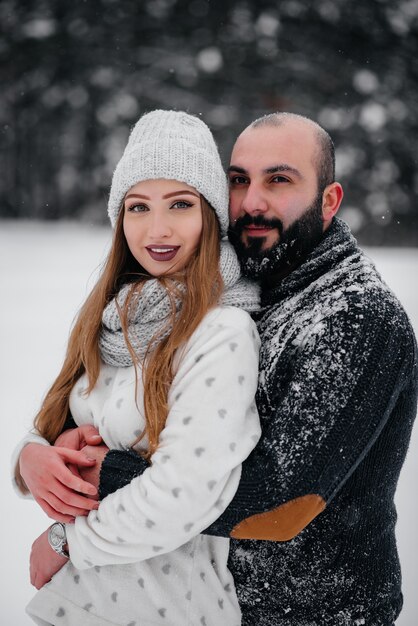 Casal brincando com neve na floresta